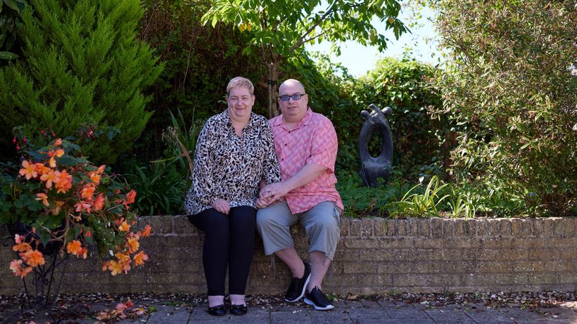Paul and Helen holding hands and sitting together